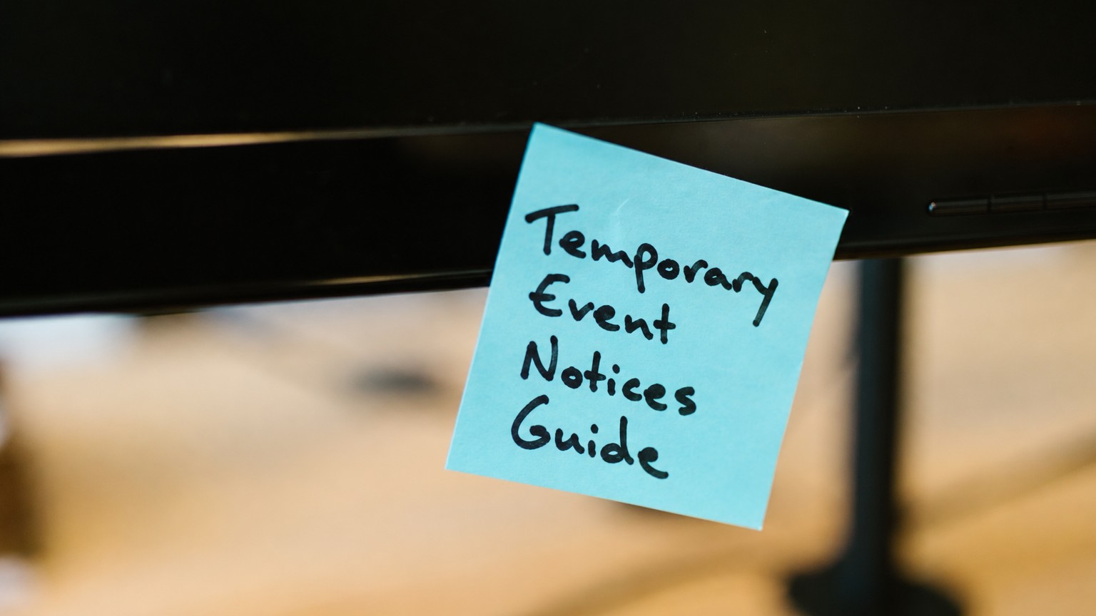 Sticky note reading Temporary Event Notices Guide on a computer monitor